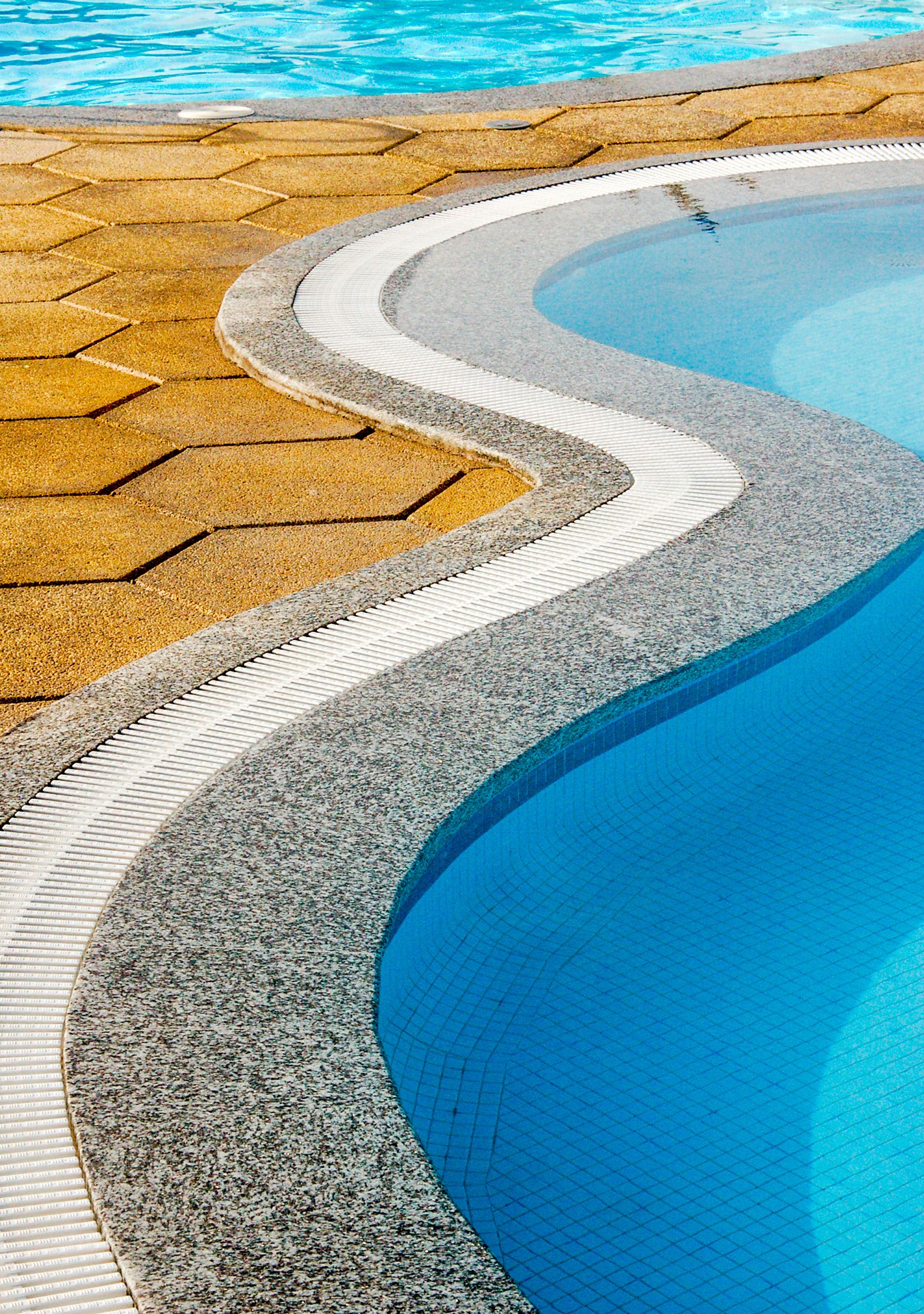 Close-up view of a resort swimming pool with unique curved stone and tile edge design.